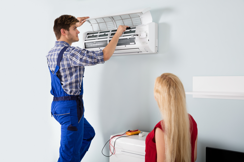technician repairing ac while women watching it